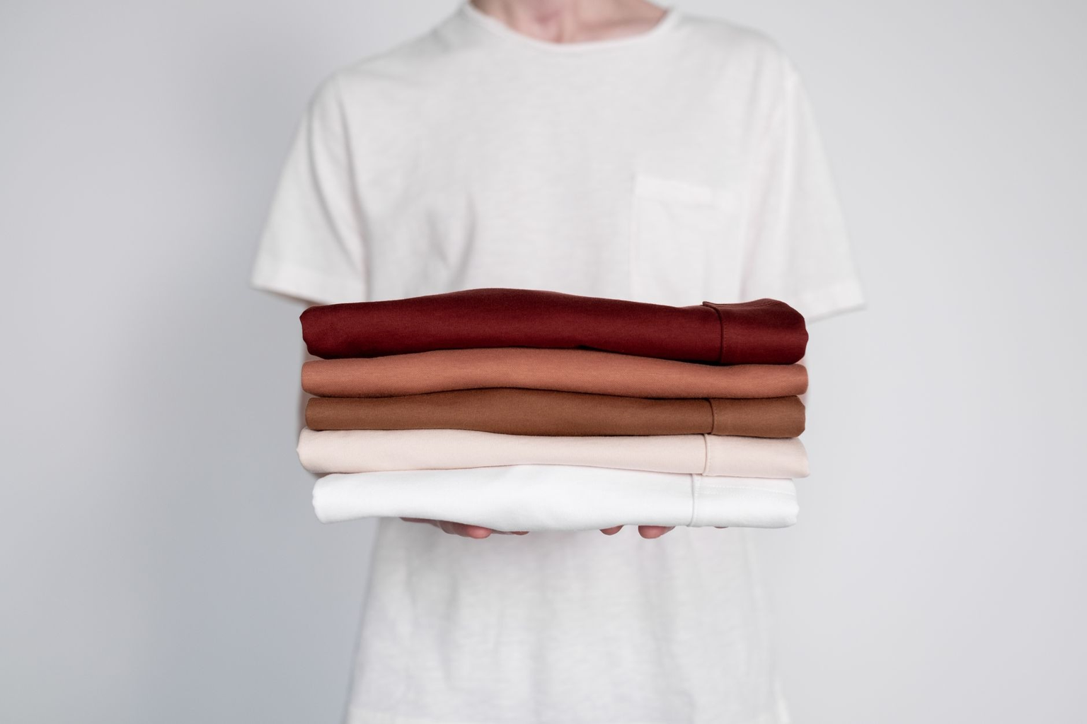A rack and folded stack of blank apparel in coordinated colours ready for decoration